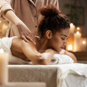 Young tender african girl smiling enjoying massage with closed eyes in spa resort.